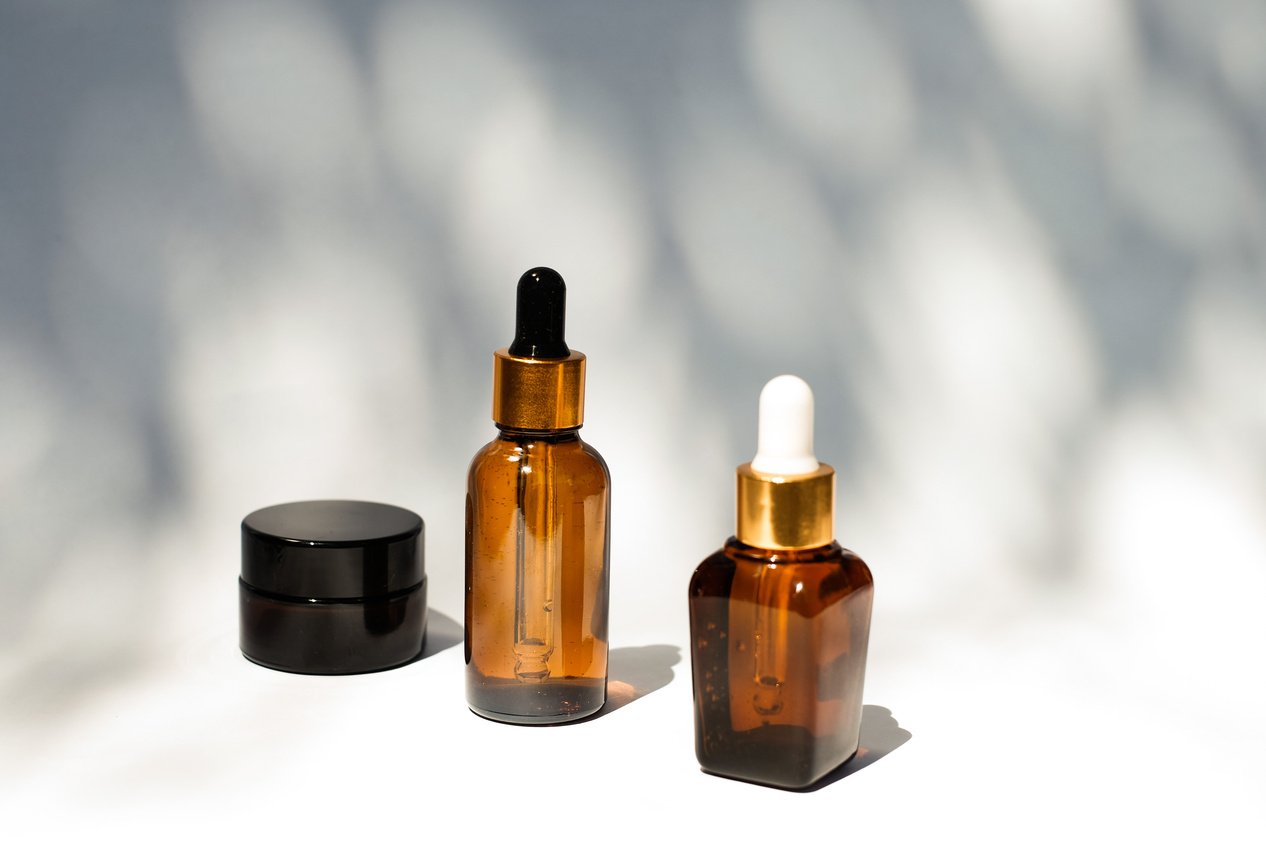 Serum Bottles and Black Cosmetic Container on White Background